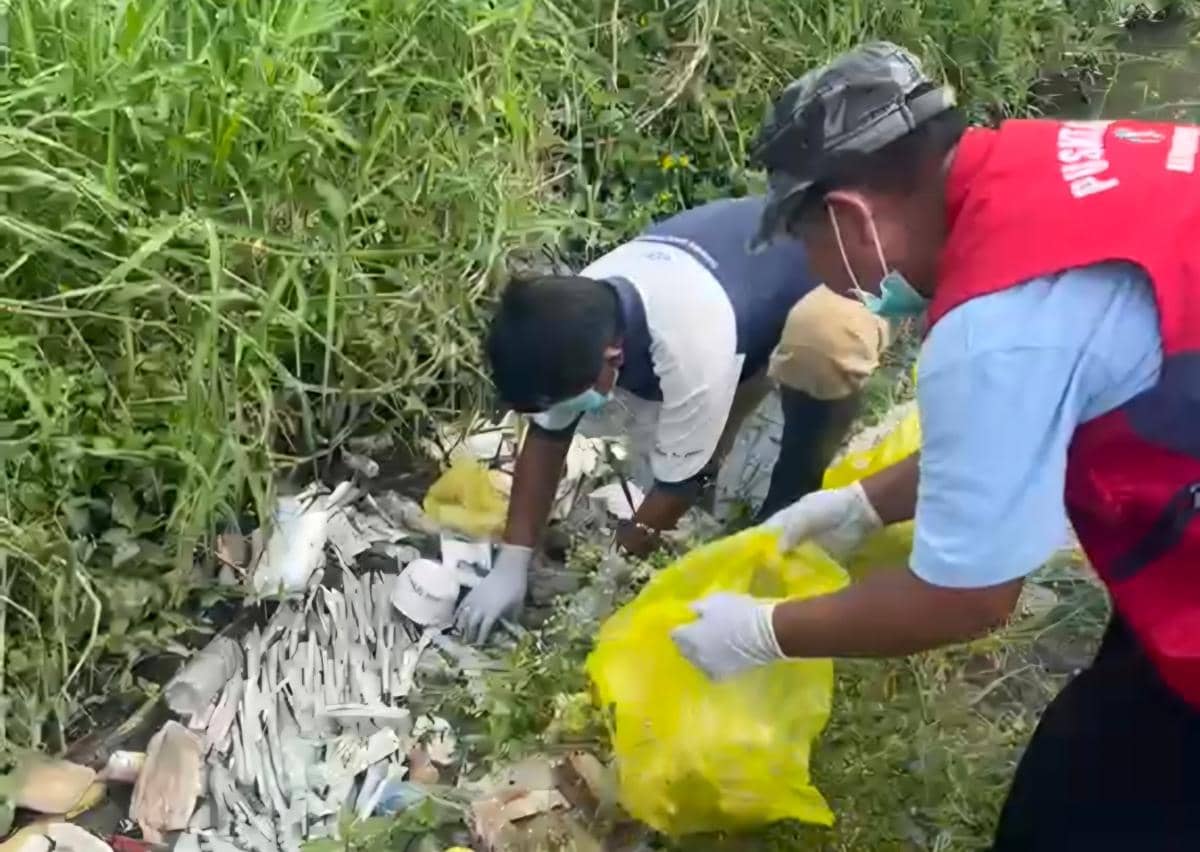 Petugas mengenakan masker dan sarung tangan sedang membersihkan limbah medis yang dibuang di saluran air Kelurahan Bumiayu, Kota Malang.