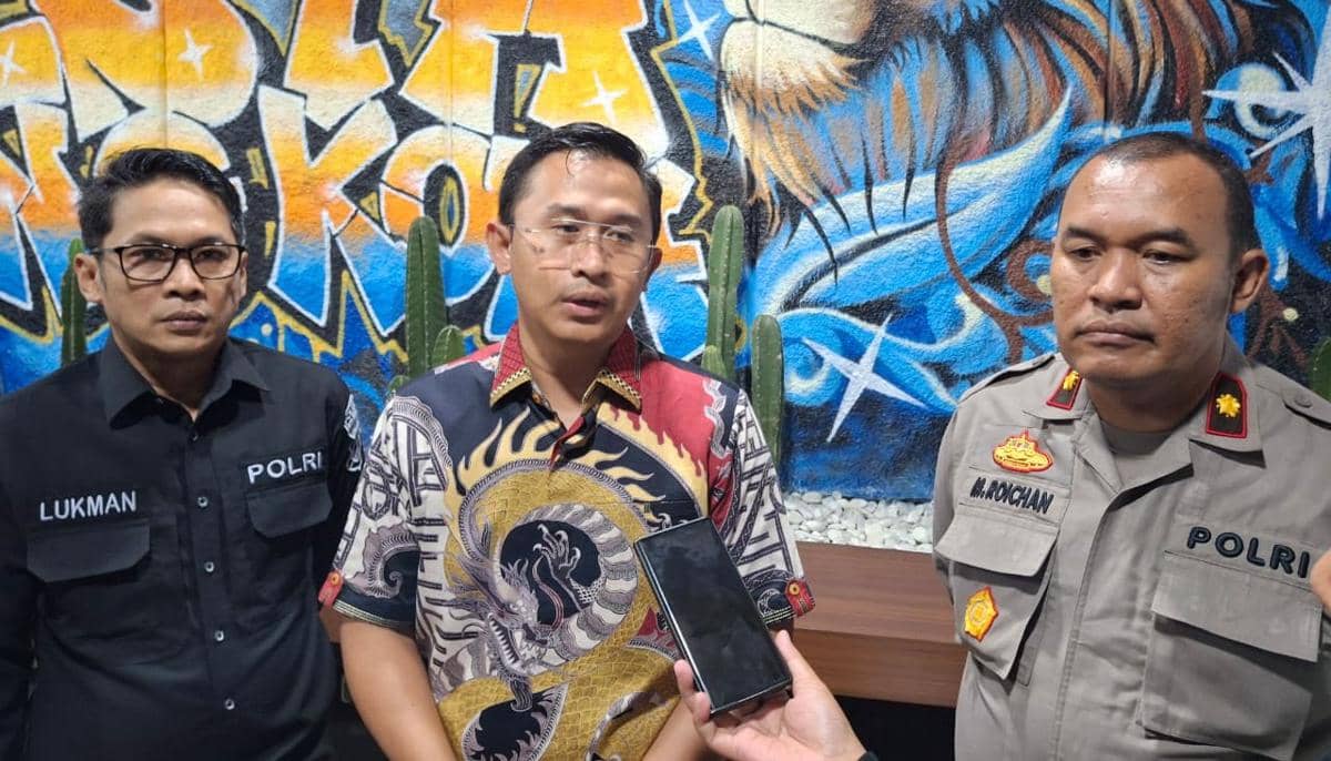 Tiga anggota kepolisian berdiri bersama di depan dinding mural berwarna cerah dengan motif grafiti dan kaktus di latar belakang.