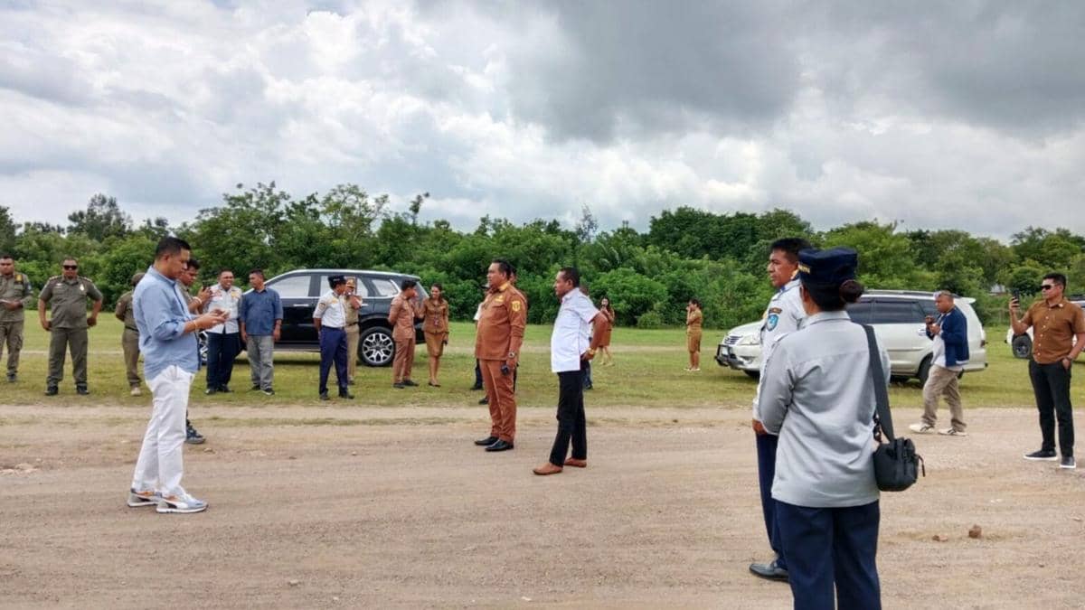 Sejumlah pejabat daerah meninjau area landasan pacu bandara dengan latar kendaraan dinas dan langit berawan di Kabupaten TTU.
