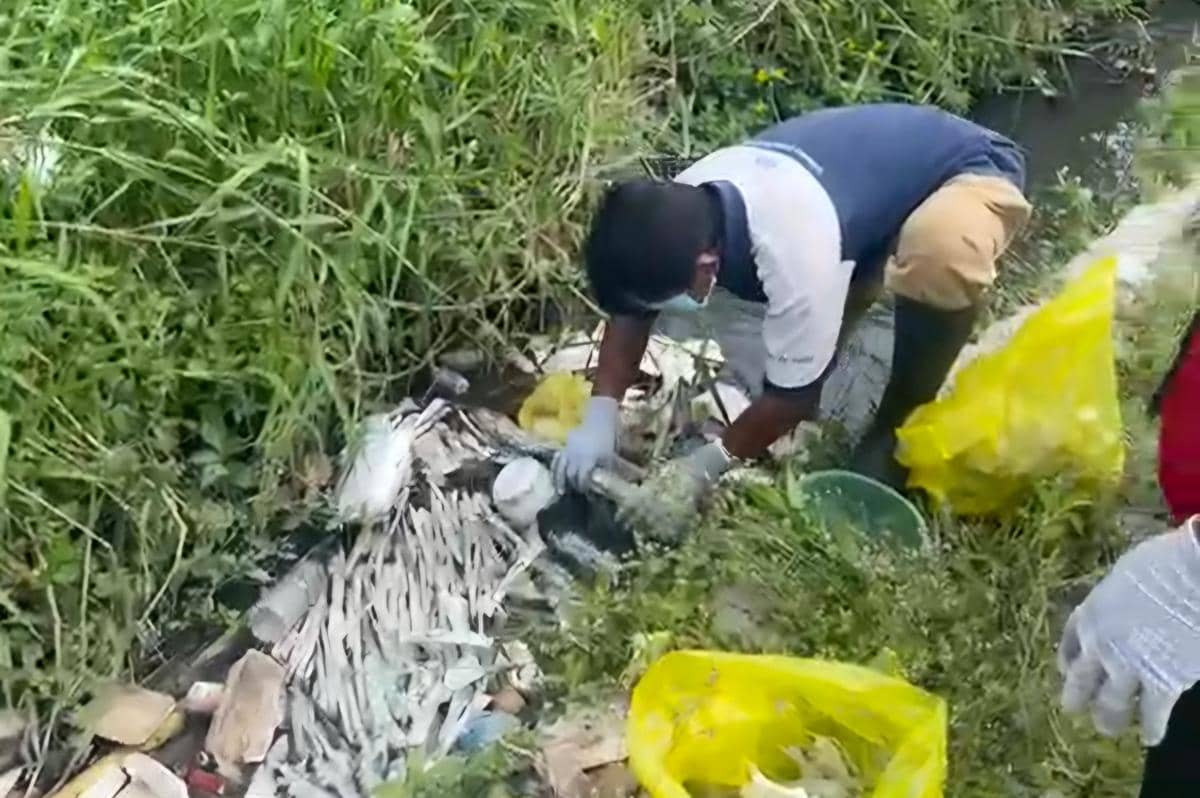Petugas mengenakan sarung tangan dan masker saat membersihkan limbah medis yang dibuang di saluran air Kelurahan Bumiayu, Kota Malang.