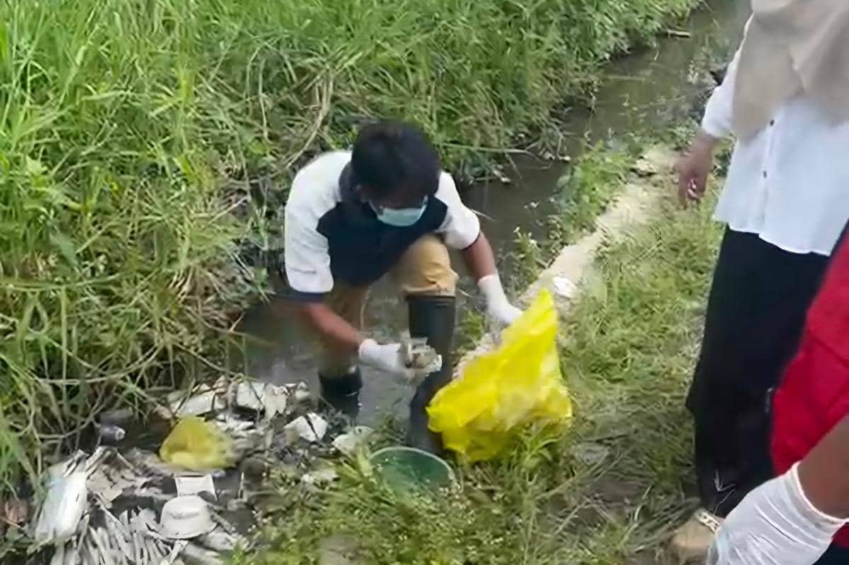 Petugas mengenakan masker dan sarung tangan membersihkan limbah medis dari saluran air di Kelurahan Bumiayu, Kota Malang.