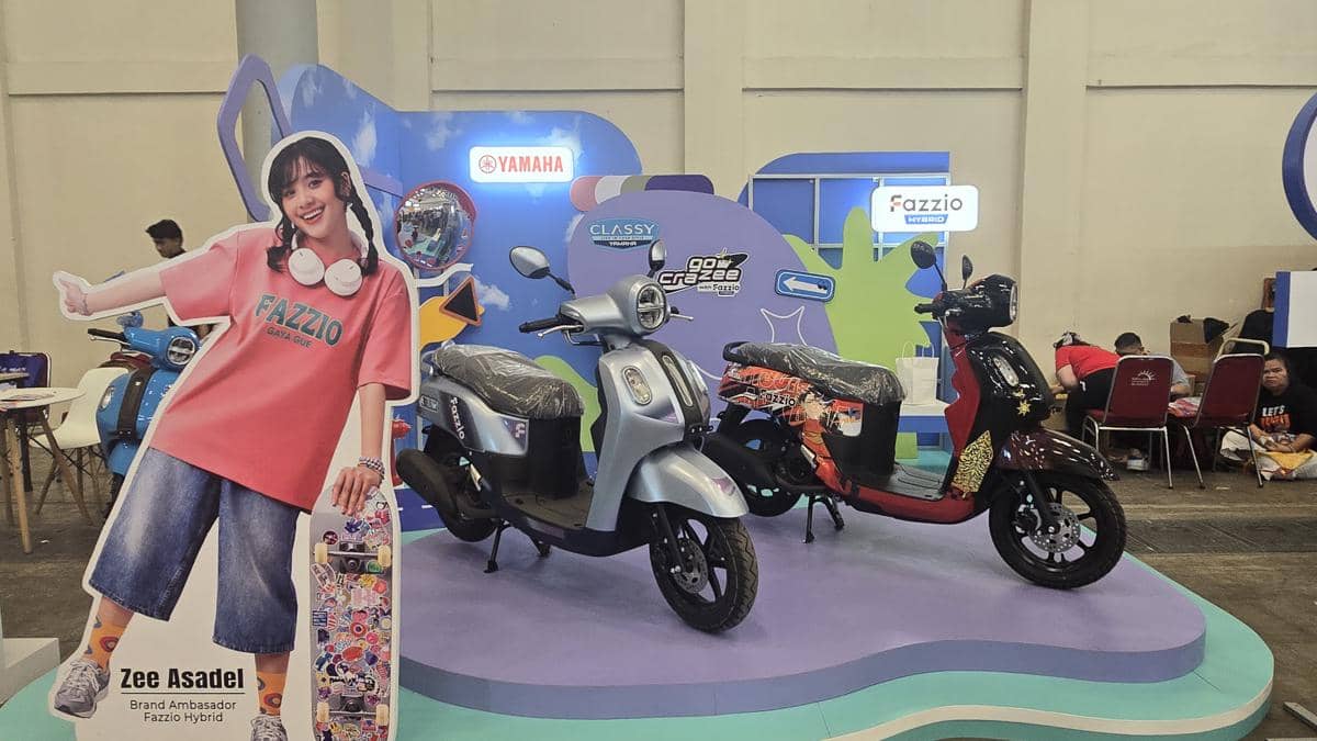 Dua motor Yamaha Fazzio dipamerkan di booth berwarna cerah pada acara Comifuro 22 dengan latar promosi dan dekorasi menarik.