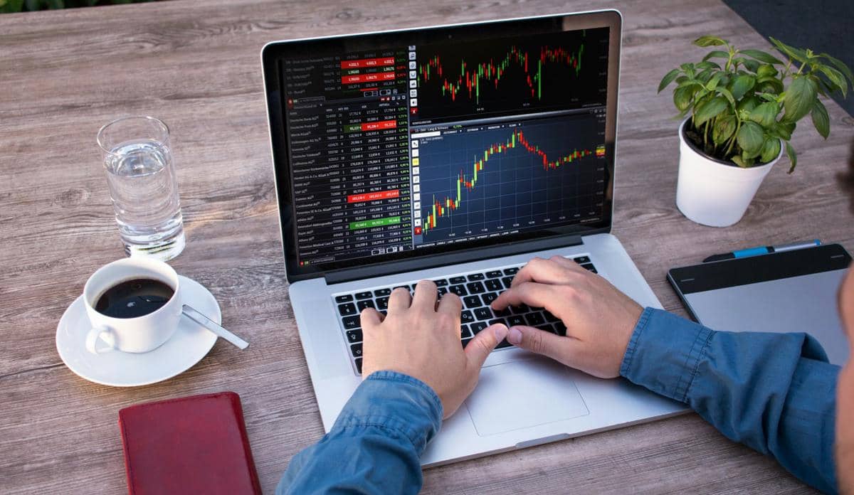 Seorang trader sedang menganalisis pergerakan grafik bursa saham di laptop