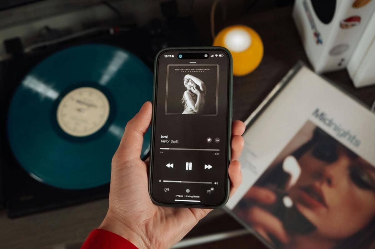 ilustrasi menikmati lagu dari Taylor Swift di smartphone dengan vinyl sebagai sentuhan analog di latar 