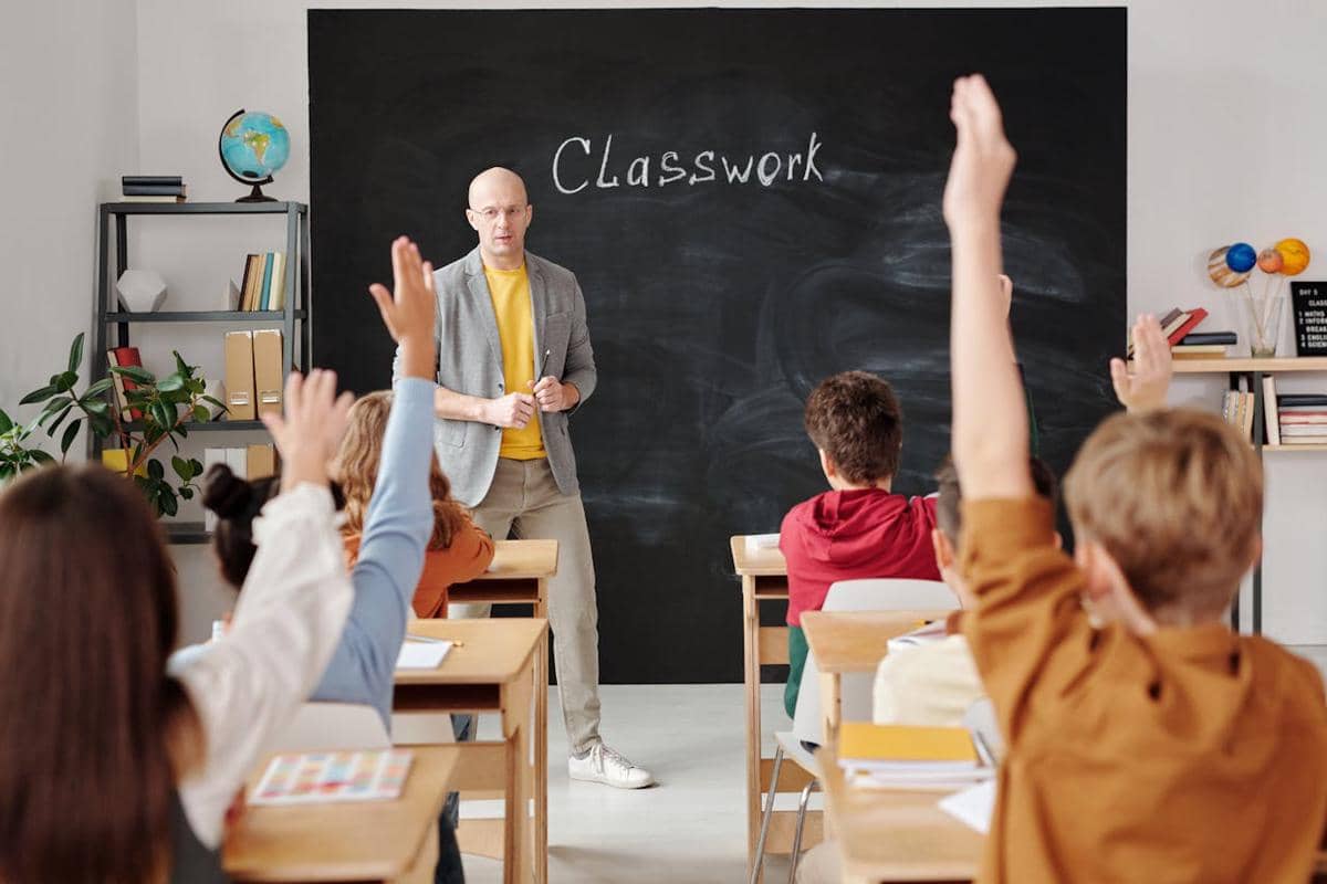 Seorang guru sedang mengajar murid di kelas. 