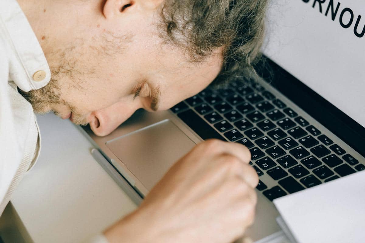 Ilustrasi seseorang duduk kelelahan di depan laptop