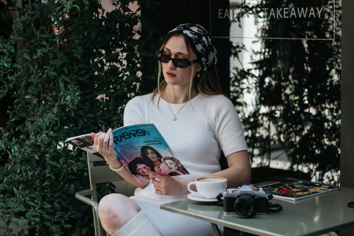 ilustrasi seorang perempuan membaca majalah cetak di kafe 