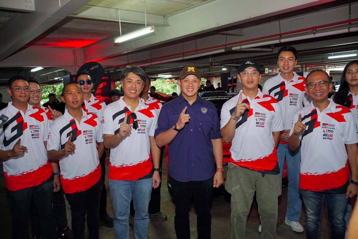 Sekelompok peserta dan panitia GR Car Meet 2026 berpose bersama di area parkir dengan mengenakan seragam putih merah bertema otomotif.