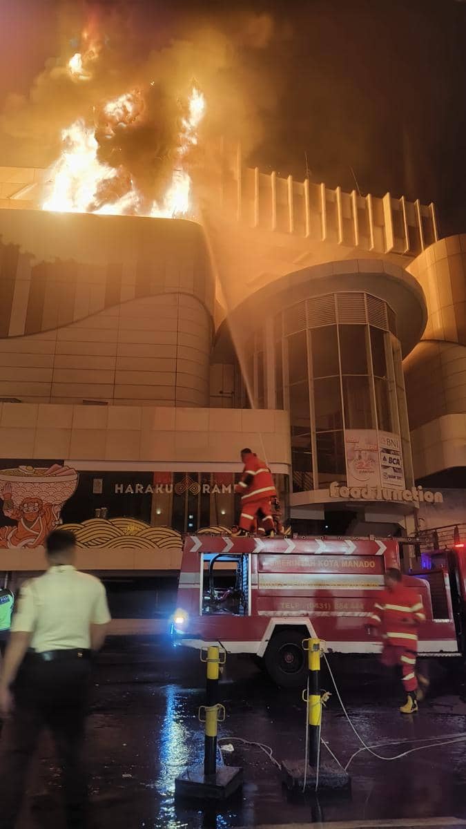 Petugas pemadam kebakaran berusaha memadamkan api besar yang melanda atap Mega Mall Manado pada malam hari.