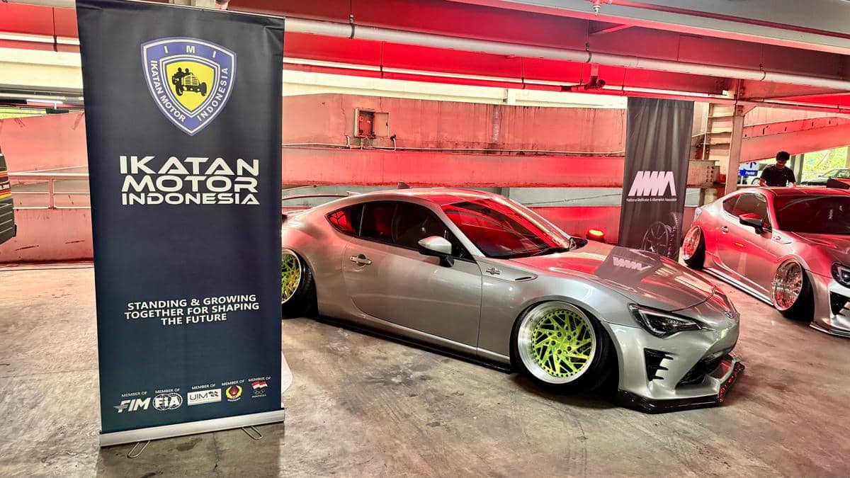 Mobil sport Toyota berwarna perak dengan velg hijau neon dipamerkan di acara Toyota GR Car Meet 2026 bersama spanduk Ikatan Motor Indonesia.