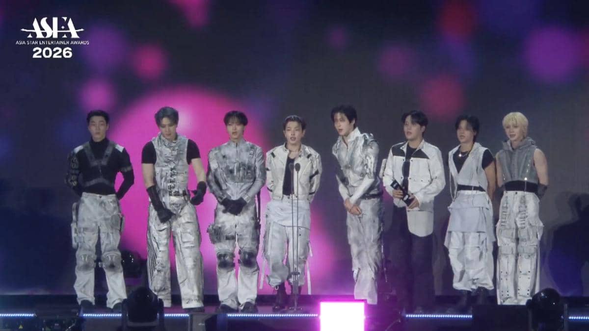 Grup musik pria mengenakan kostum panggung bernuansa perak dan putih berdiri di atas panggung Asia Star Entertainer Awards 2026.