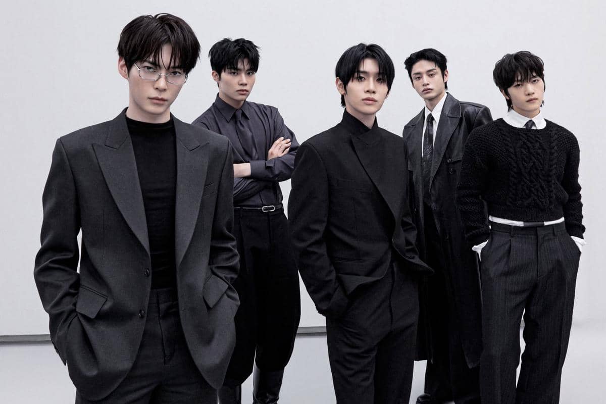 Lima anggota grup ZEROBASEONE berpose dengan gaya elegan mengenakan setelan formal berwarna gelap di latar belakang abu-abu.