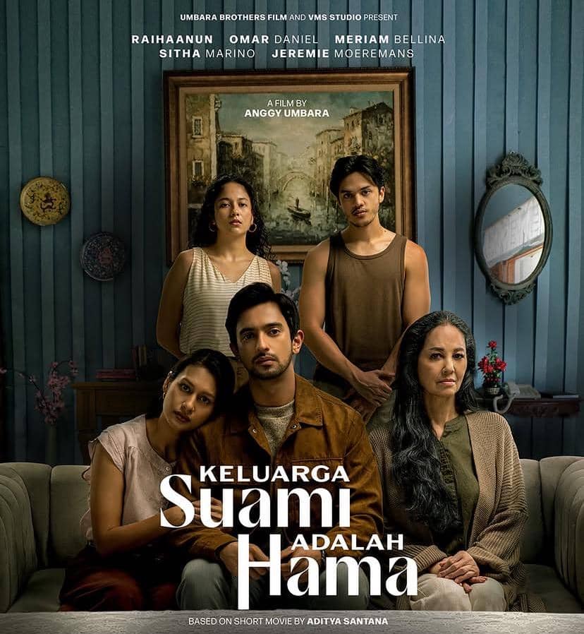 Poster film Keluarga Suami Adalah Hama menampilkan lima pemeran utama duduk dan berdiri di ruang tamu dengan latar dinding biru.