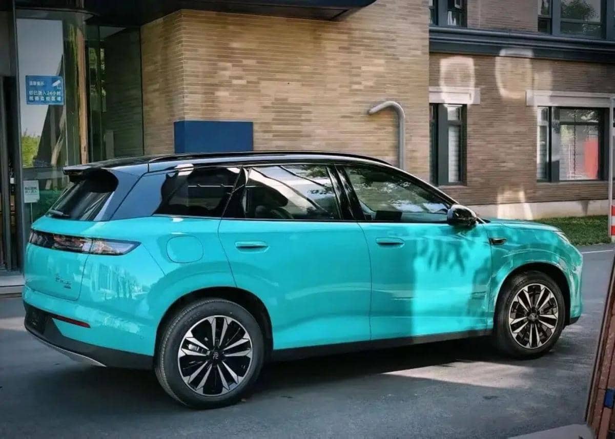 Mobil listrik berwarna biru toska dengan atap hitam diparkir di depan gedung modern, mengusung teknologi Blade Battery 2.0.