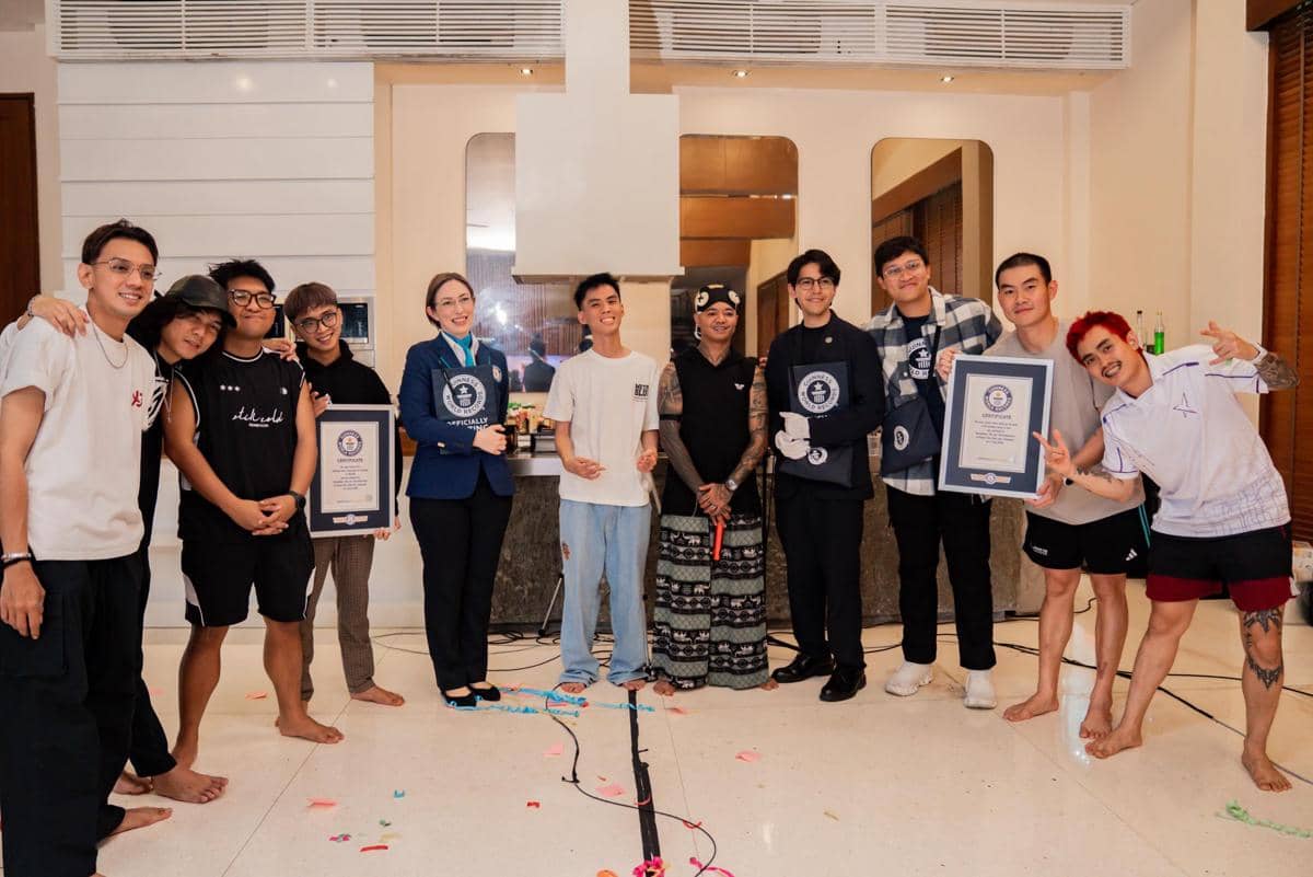 Sekelompok orang berpose bersama di dalam ruangan, beberapa memegang sertifikat penghargaan Guinness World Records dengan suasana bahagia.
