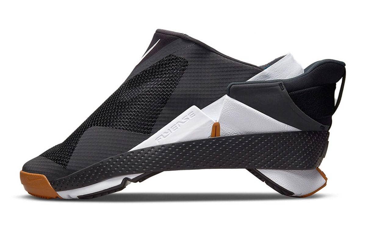 Sepatu Nike Go FlyEase berwarna hitam, putih, dan oranye dengan desain tanpa tali yang dapat dibuka lipat untuk kemudahan pemakaian.