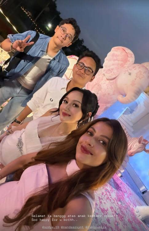 Empat orang berpose bersama di acara gender reveal bertema warna pink dengan dekorasi balon dan patung gajah di latar belakang.