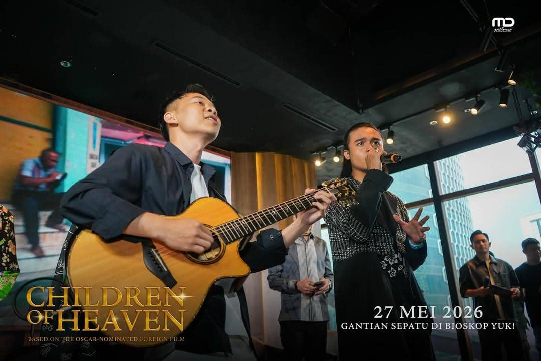 Dua musisi tampil di atas panggung, satu memainkan gitar akustik dan satu bernyanyi dengan mikrofon dalam acara promosi film Children of Heaven.