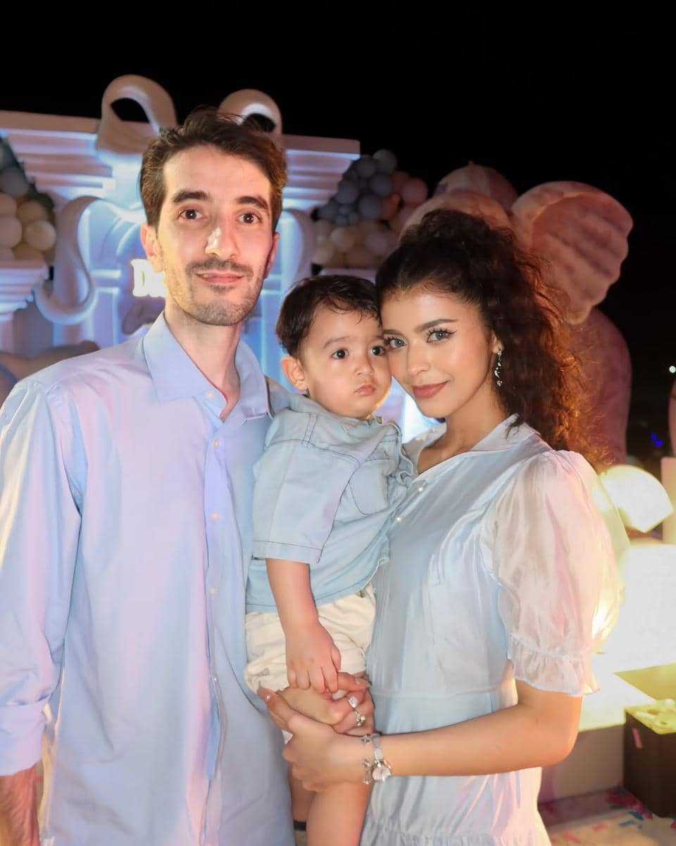 Sebuah keluarga terdiri dari pria, wanita, dan anak kecil berpose bersama mengenakan pakaian bernuansa biru di acara gender reveal.