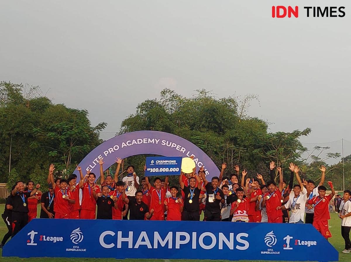 Tim sepak bola muda merayakan kemenangan di Elite Pro Academy Super League 2025/26 dengan trofi dan hadiah di atas panggung juara.