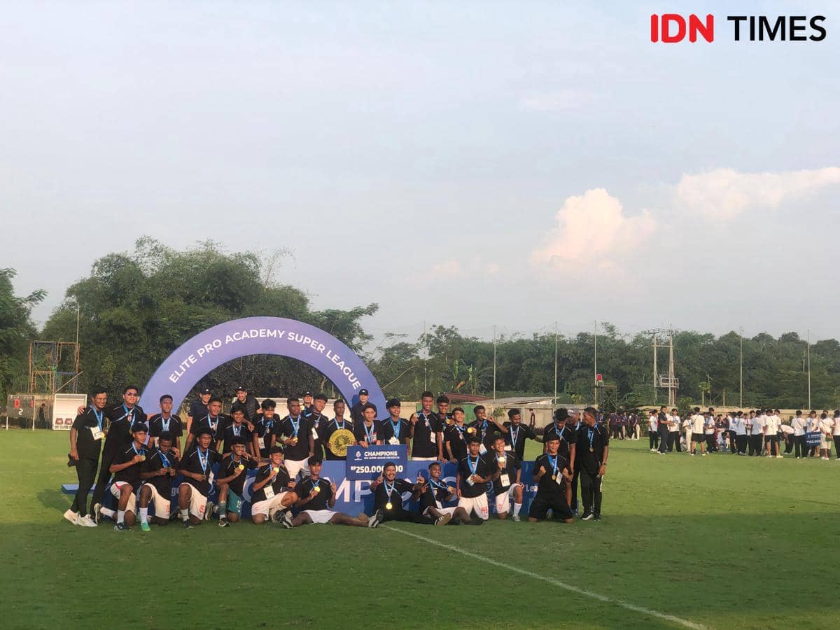 Para pemain dan staf tim sepak bola berpose bersama trofi juara di lapangan setelah turnamen Elite Pro Academy Super League 2025/26.