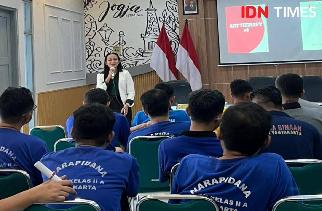 Seorang perempuan berbicara di depan narapidana yang mengenakan seragam biru dalam sesi art therapy di Yogyakarta.