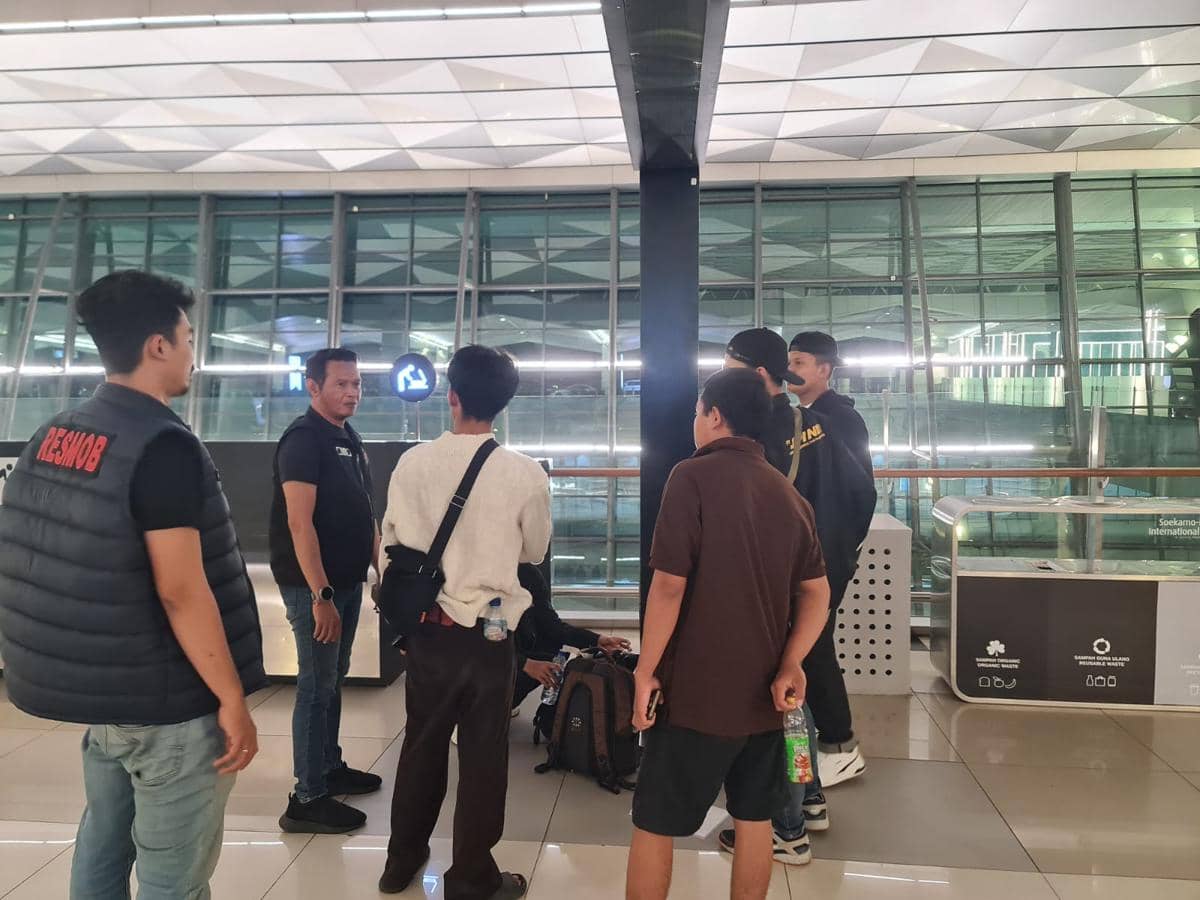 Petugas kepolisian mengamankan sekelompok calon jemaah haji ilegal di area terminal Bandara Soekarno-Hatta pada malam hari.