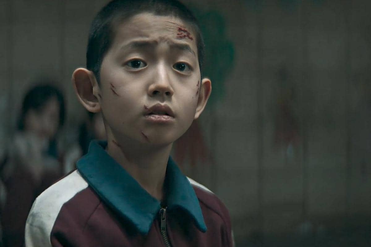 Anak laki-laki dengan luka di wajah mengenakan jaket olahraga marun dan biru dalam adegan drama The Wonderfools.