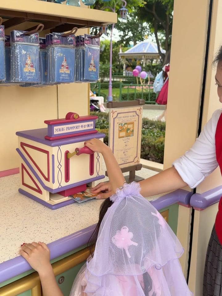 Seorang anak mengenakan kostum ungu sedang bermain di area Magic Passport di Disneyland Hong Kong bersama seorang pendamping dewasa.