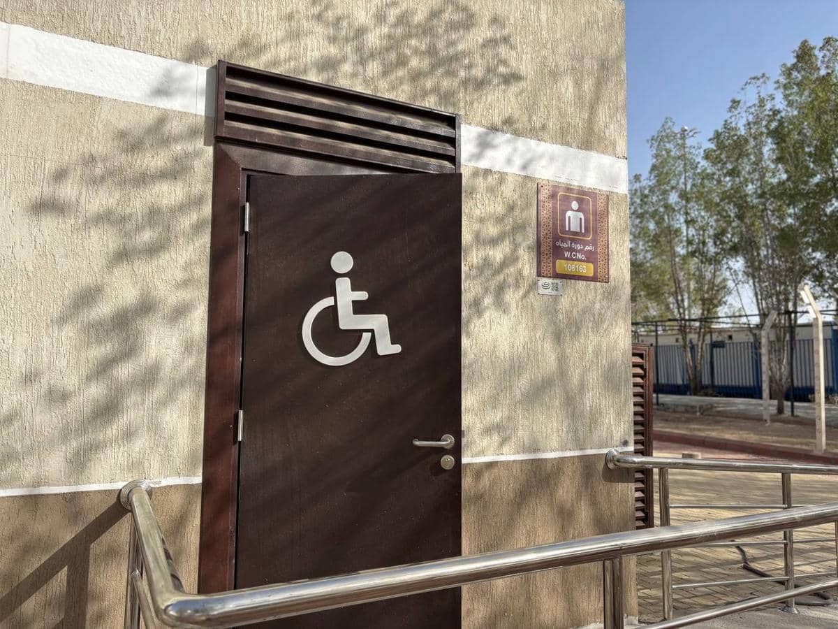 Pintu toilet di Arafah dengan simbol kursi roda dan pegangan besi di sekitarnya untuk akses difabel menjelang Haji 2026.