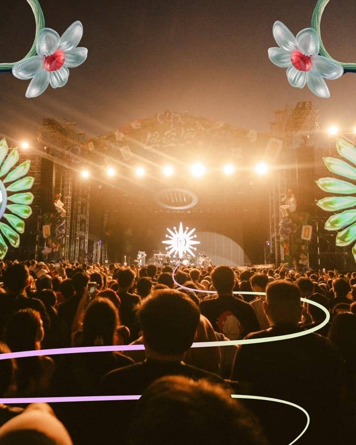 Kerumunan penonton menikmati konser musik di panggung besar LaLaLa Festival dengan pencahayaan hangat dan dekorasi bunga artistik.