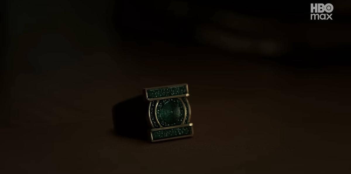 Cincin berwarna hijau dengan desain futuristik bercahaya redup di atas permukaan gelap, menampilkan nuansa misterius.