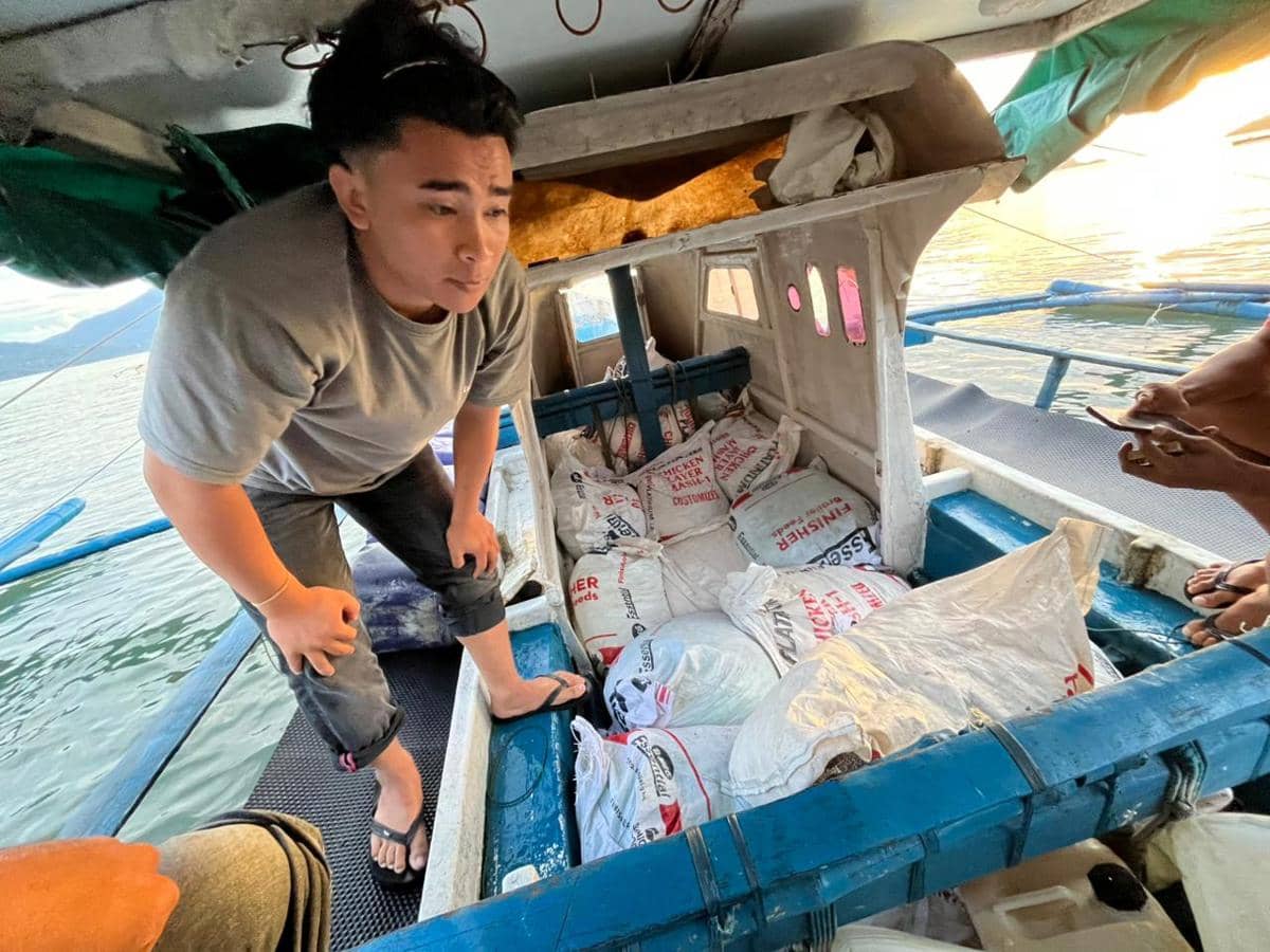 Seorang pria di atas perahu kecil memeriksa sejumlah karung berisi bahan kimia yang diduga sianida di perairan Kepulauan Sitaro.