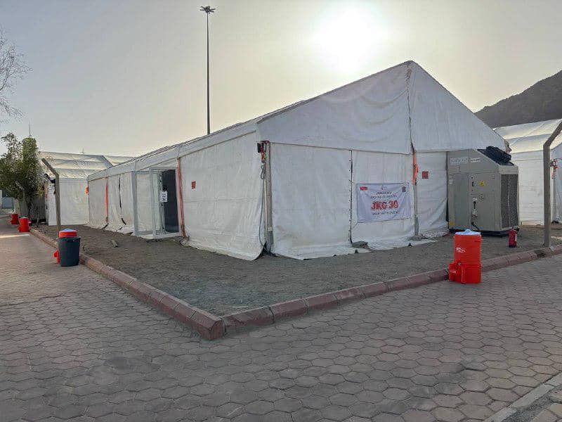 Deretan tenda putih jemaah haji Indonesia di Arafah dengan pendingin udara dan tempat sampah di sekitarnya pada siang hari.