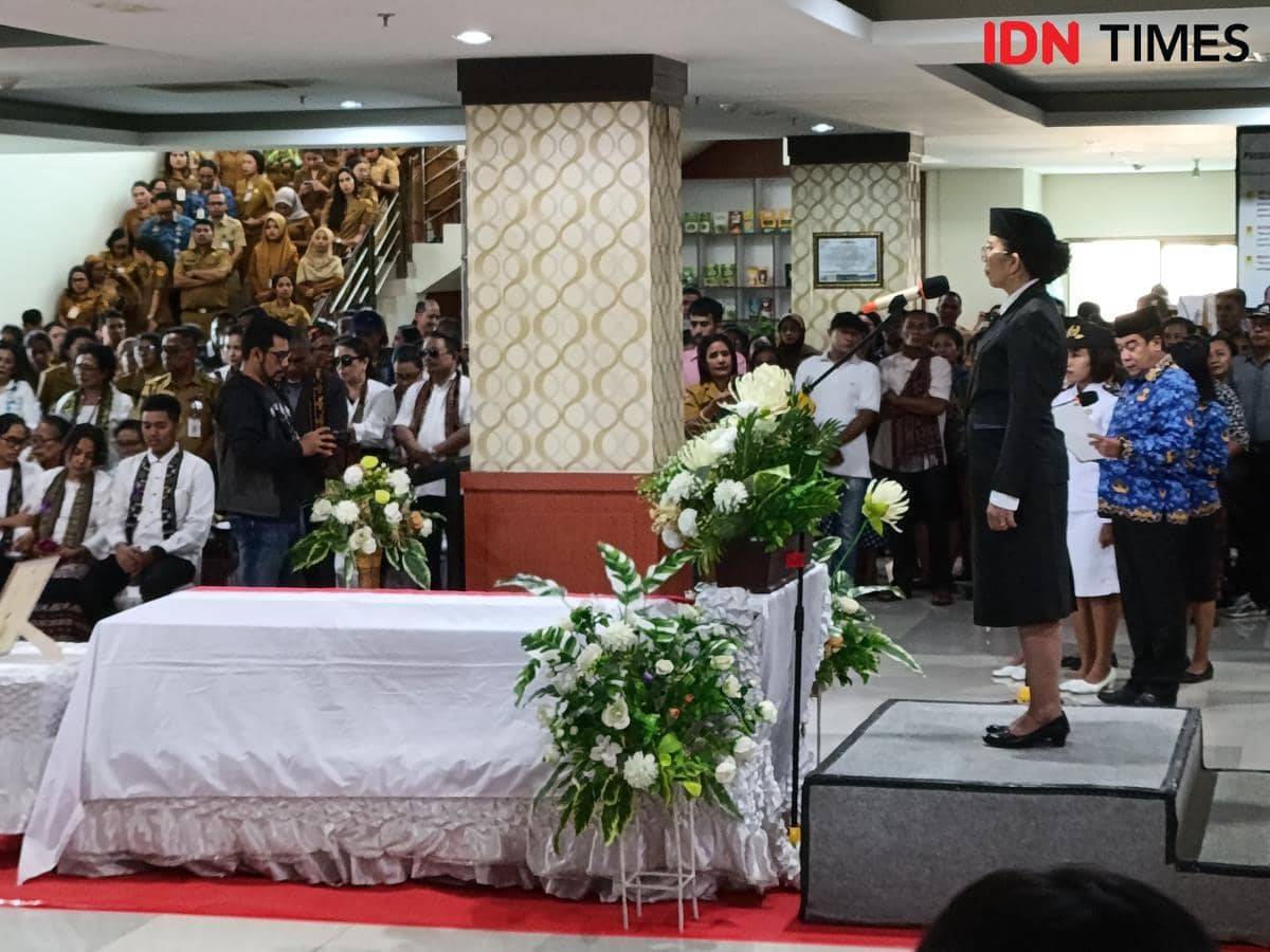 Upacara penghormatan terakhir kepada Kadis PMD NTT Alexander Koroh dengan peti jenazah dihiasi bunga dan peserta berpakaian dinas.