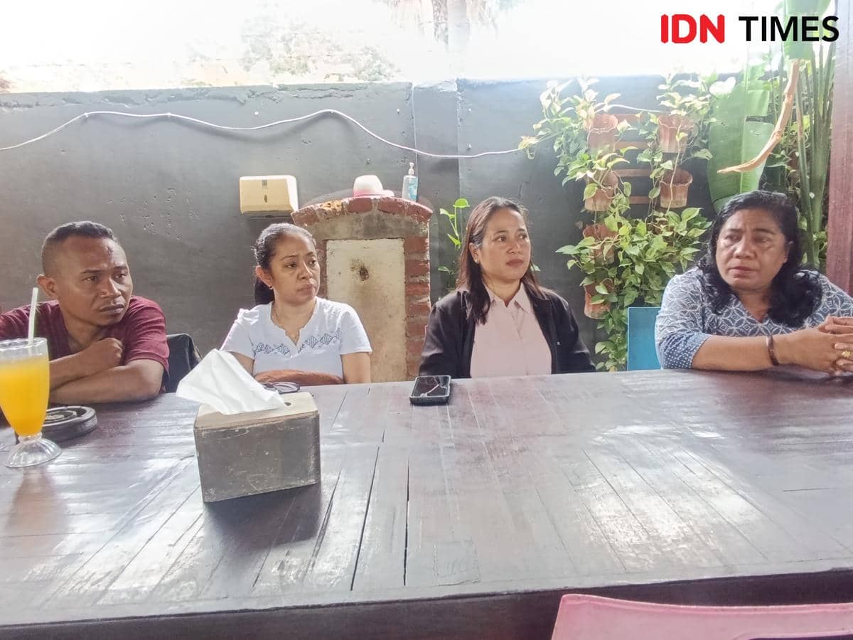 Empat orang duduk di meja kayu dalam suasana pertemuan informal di ruangan terbuka dengan latar dinding abu-abu dan tanaman hias.