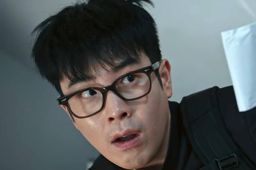 Seorang pria berkacamata hitam dengan ekspresi terkejut dalam adegan drama Korea Teach You a Lesson di Netflix Indonesia.