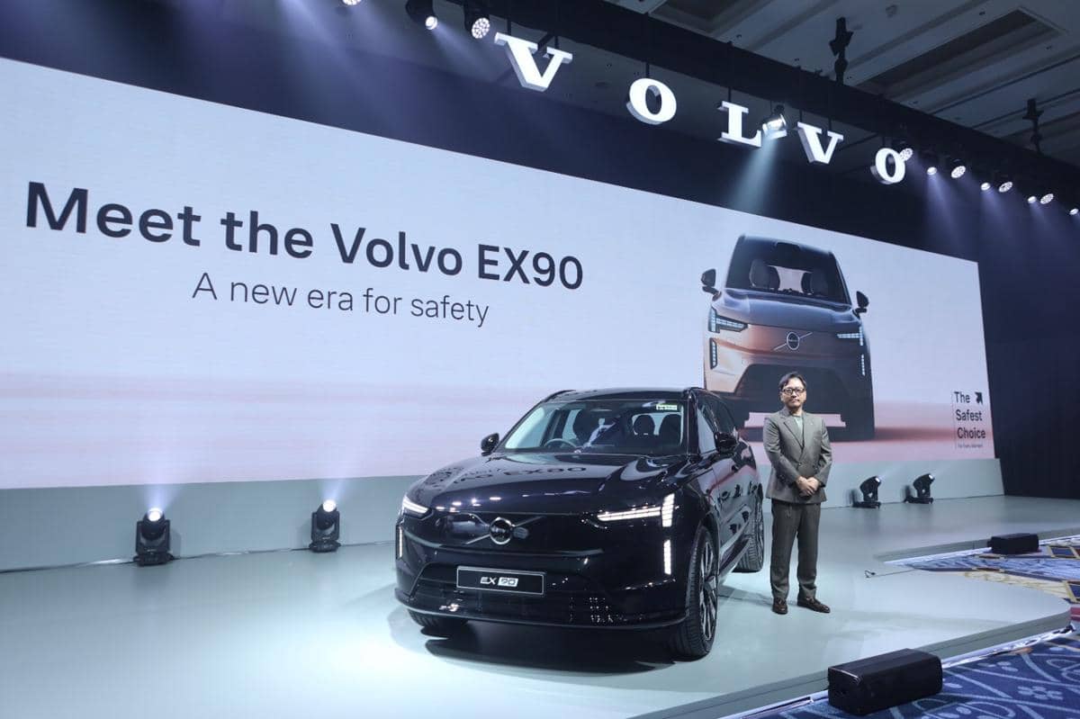 Peluncuran mobil listrik Volvo EX90 di Indonesia dengan latar layar besar bertuliskan 'Meet the Volvo EX90' dan seorang pria berdiri di samping mobil.