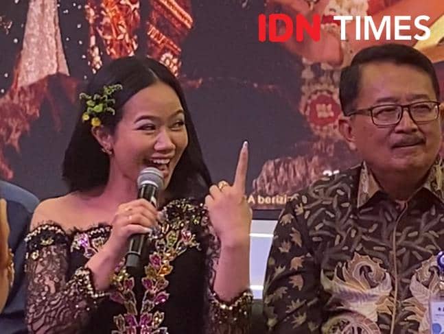 Seorang perempuan berbaju hitam berhias bunga berbicara dengan mikrofon di tangan saat konferensi pers Pagelaran Sabang Merauke 2026.