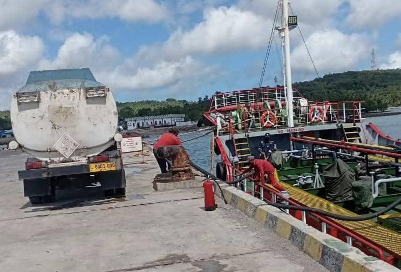 Kapal pengangkut BBM bersandar di pelabuhan Rote Ndao dengan truk tangki dan pekerja yang sedang melakukan proses distribusi bahan bakar.