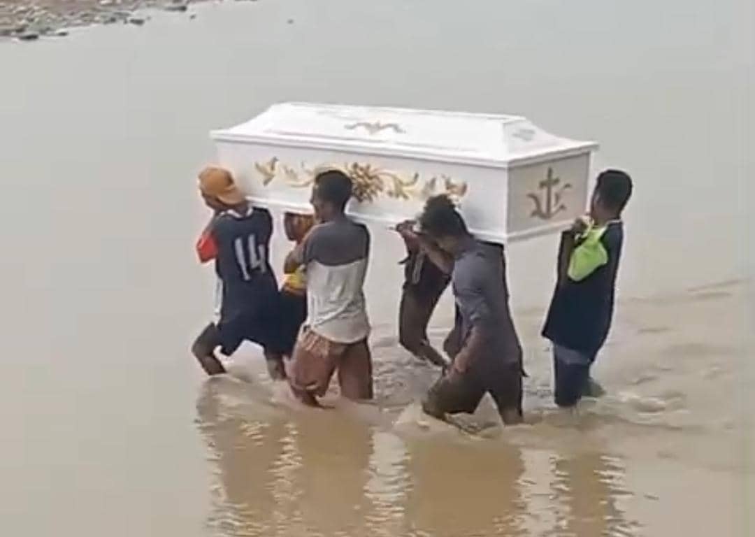 Beberapa warga Amfoang di Kupang, NTT, memikul peti jenazah melintasi sungai dangkal karena tidak adanya jembatan penghubung.