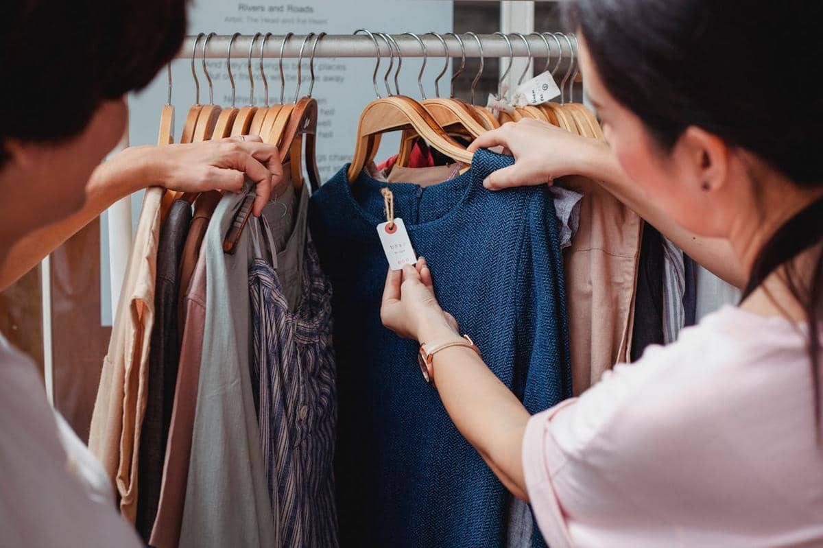 ilustrasi dua wanita sedang melihat pakaian di sebuah butik