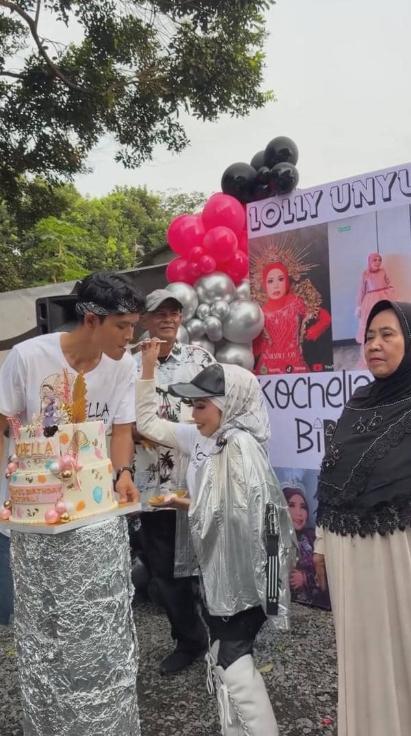 Perayaan ulang tahun bertema luar ruangan dengan dekorasi balon merah, hitam, dan perak serta kue ulang tahun berhiaskan ornamen warna-warni.