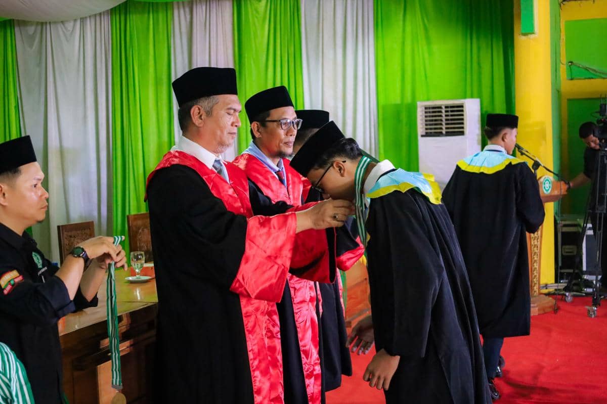 Seorang santri menerima kalung kelulusan dari pengajar berseragam toga merah dalam acara wisuda di Pesantren Darularafah Raya.