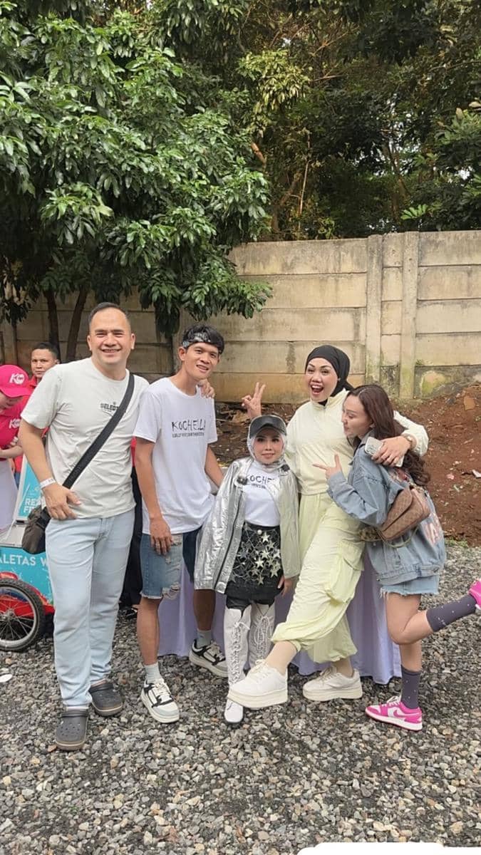Sekelompok orang berpose bersama di luar ruangan saat perayaan ulang tahun Lolly Unyu, dengan latar pepohonan dan tembok beton.