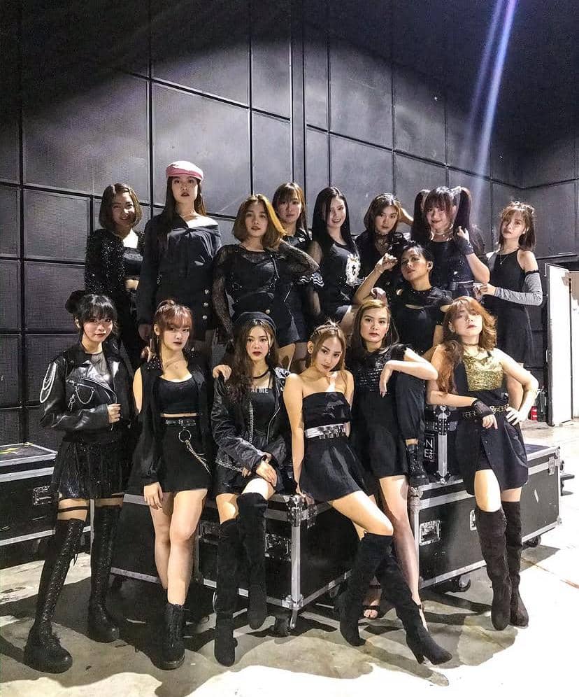 Grup beranggotakan banyak perempuan mengenakan busana hitam bergaya modern berpose bersama di depan dinding hitam dalam ruangan.