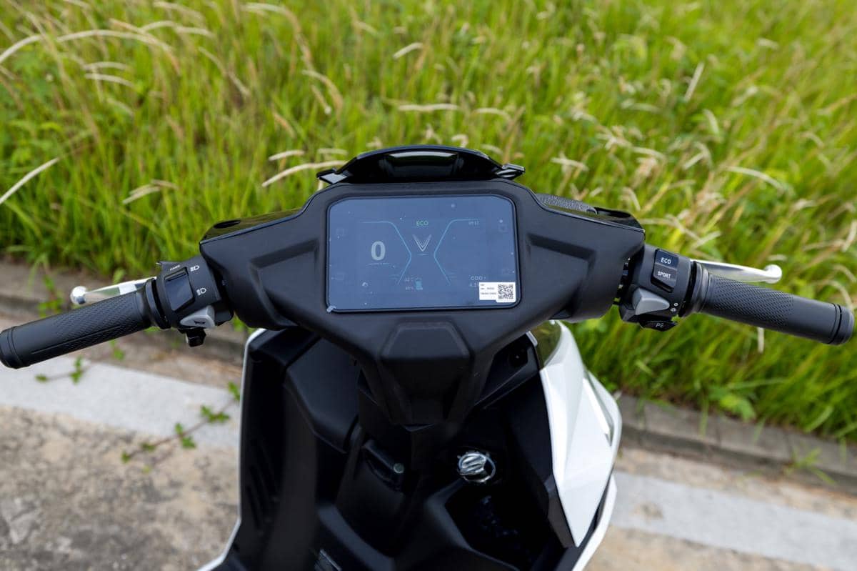 Panel instrumen digital motor listrik VinFast dengan layar berwarna menampilkan mode berkendara dan indikator kecepatan.