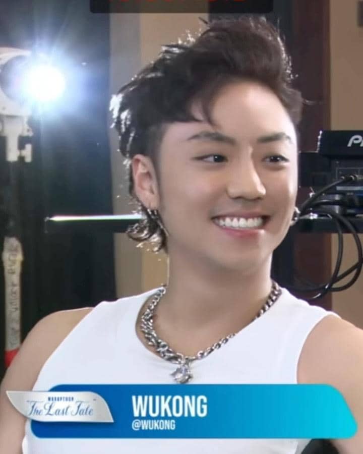 Seorang pria mengenakan tank top putih dan kalung rantai perak tersenyum di depan kamera saat acara Marapthon Season 3.