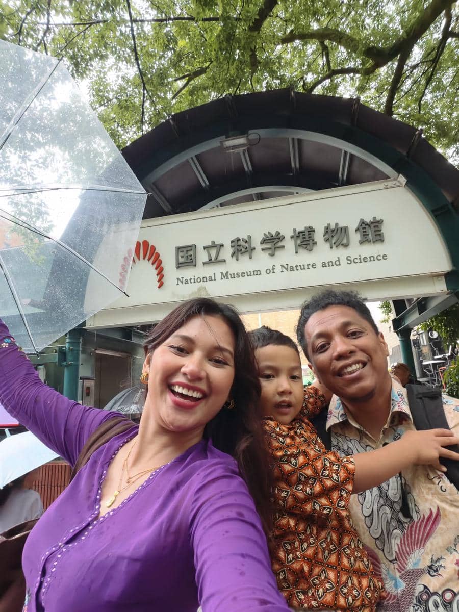 Keluarga berpose ceria di depan National Museum of Nature and Science di Jepang, mengenakan pakaian tradisional batik dan kebaya.