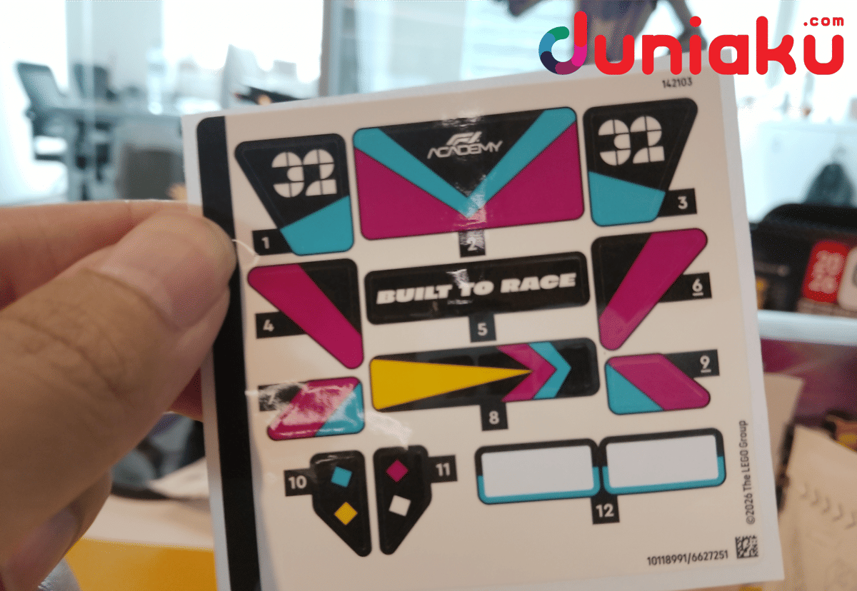 Tangan memegang lembar stiker Speed Champions F1 Academy LEGO Race Car dengan desain warna hitam, magenta, biru, dan kuning.